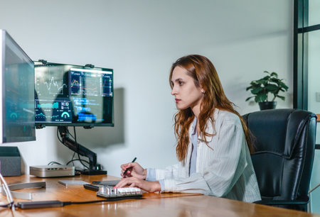 Financial analyst working on multiple monitors displaying stock market charts, financial data, and...