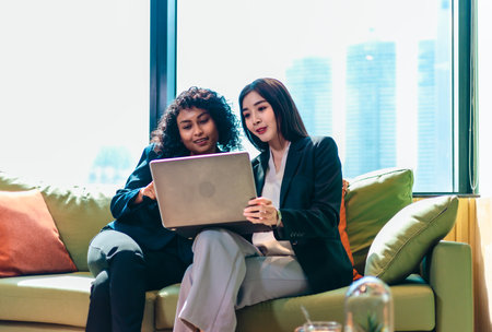Two businessperson engage in a collaborative discussion while working on a laptop in a modern...