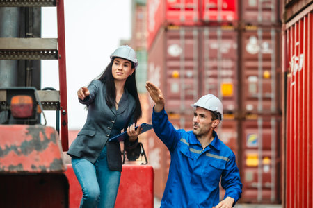 Industrial container workers discussing eco-friendly logistics strategies. Reducing fuel consumption, lowering carbon footprints, and implementing zero-emission practices in supply chain operations.の写真素材