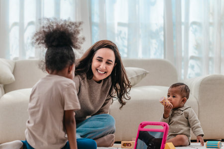 A joyful mother, playing and laughing with her two young daughters. The scene captures a warm, loving family moment with toys scattered around, highlighting early childhood interaction and bonding.の写真素材