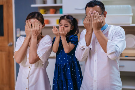 A cheerful Asian family shares a loving and joyful moment together in a modern kitchen at home, reflecting warmth, connection, and everyday family lifeの写真素材