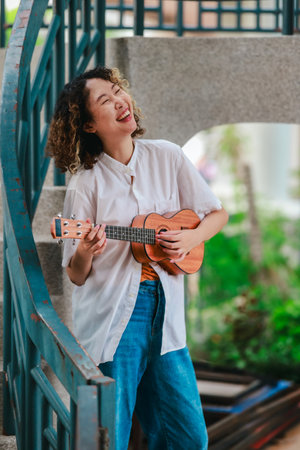An Asian woman with curly, two-tone hair plays ukulele in an outdoor setting, radiating happiness...