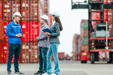 The female manager supervises and discusses logistics with two male workers at shipping container...