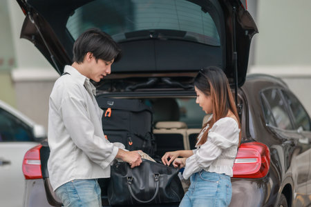 An Asian couple is seen happily packing a car trunk with bags and gear as they prepare for a picnic outing.  A candid and joyful moment of planning and teamwork before a relaxing day outdoors.の写真素材