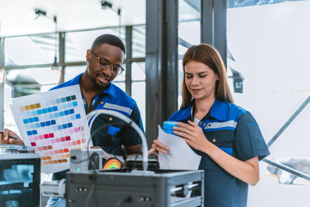 Engineer review color swatch guide while standing beside 3D printer, selecting hues for recycled 3D...