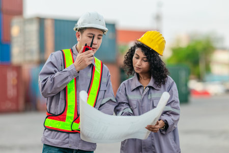 Industrial container workers discuss sustainable logistics operations. Analyzing blueprint, including zero emissions, reducing fuel consumption and carbon footprint in supply chain managementの写真素材