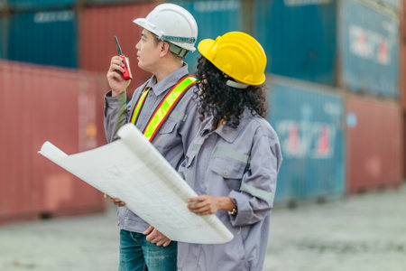 Industrial container workers discuss sustainable logistics operations. Analyzing blueprint,...