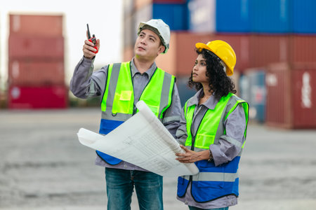 Industrial container workers discuss sustainable logistics operations. Analyzing blueprint,...