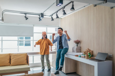 Team members enthusiastically celebrate a successful project in a modern office setting. The moment captures teamwork, motivation, and the joy of achieving goals in a startup environment.の写真素材
