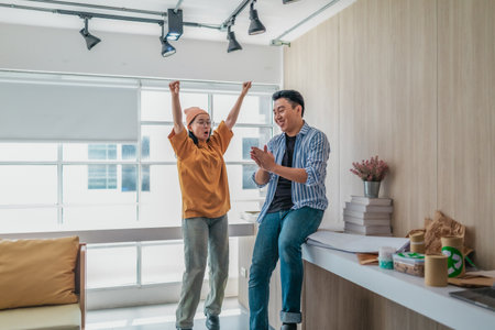 Team members enthusiastically celebrate a successful project in a modern office setting. The moment captures teamwork, motivation, and the joy of achieving goals in a startup environment.の写真素材