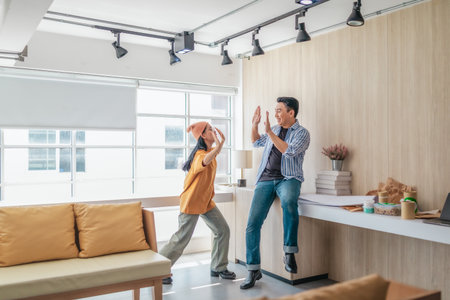 Team members enthusiastically celebrate a successful project in a modern office setting. The moment captures teamwork, motivation, and the joy of achieving goals in a startup environment.の写真素材