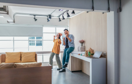 Team members enthusiastically celebrate a successful project in a modern office setting. The moment captures teamwork, motivation, and the joy of achieving goals in a startup environment.の写真素材
