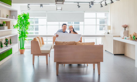 Two professionals review a large planning sheet together in a bright, modern workspace. The scene reflects teamwork, strategic thinking, and collaborative project development in a startup environmentの写真素材
