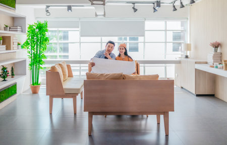 Two professionals review a large planning sheet together in a bright, modern workspace. The scene reflects teamwork, strategic thinking, and collaborative project development in a startup environmentの写真素材