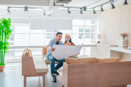 Two professionals review a large planning sheet together in a bright, modern workspace. The scene...