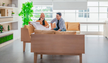 Two professionals review a large planning sheet together in a bright, modern workspace. The scene...