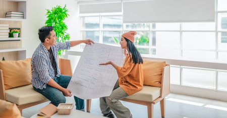 Two professionals review a large planning sheet together in a bright, modern workspace. The scene reflects teamwork, strategic thinking, and collaborative project development in a startup environmentの写真素材