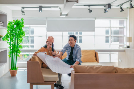 Two professionals review a large planning sheet together in a bright, modern workspace. The scene reflects teamwork, strategic thinking, and collaborative project development in a startup environmentの写真素材