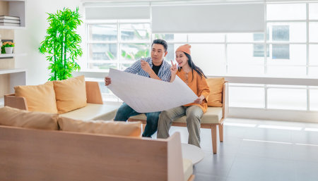 Two professionals review a large planning sheet together in a bright, modern workspace. The scene reflects teamwork, strategic thinking, and collaborative project development in a startup environmentの写真素材