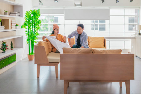 Two professionals review a large planning sheet together in a bright, modern workspace. The scene reflects teamwork, strategic thinking, and collaborative project development in a startup environmentの写真素材