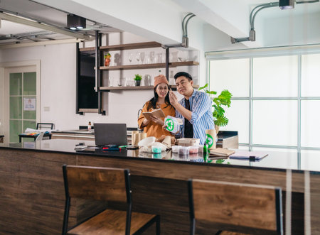 Two entrepreneurs review sustainable packaging samples in a modern workspace. Surrounded by eco-friendly materials and product prototypes, they discuss ideas for product development and brandingの写真素材