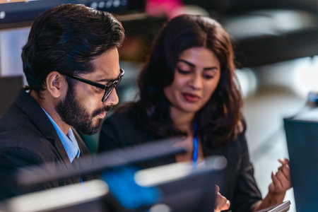 Two professionals analyze and discuss programming code displayed on screen in modern tech workspace....