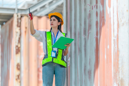Mixed-race female technician performs field inspection of site office containers. Representing the...