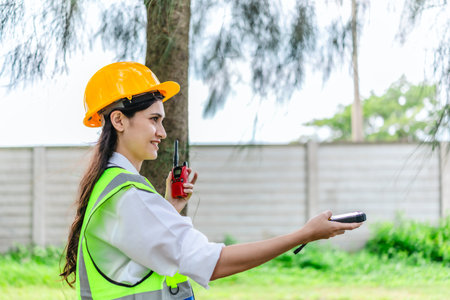 Female environmental fieldworker uses GPS land meter to survey tree positions, spacing, height in...