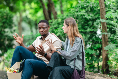 African male employee carries box of office belongings while female coworker encourages him outdoors. Reflecting job loss during an economic downturn and power of workplace support and resilienceの写真素材