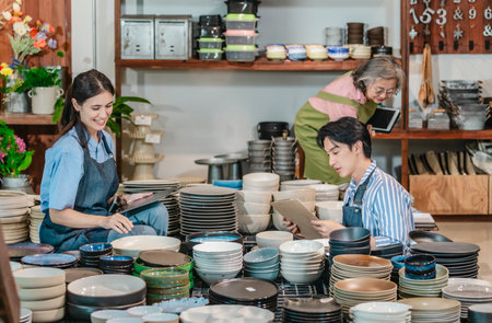 In a family business, a mother, son, and daughter manage a ceramic shop together, arranging tableware displays and coordinating daily operations for both retail and wholesale sales.の写真素材
