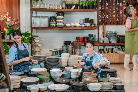 In a family business, a mother, son, and daughter manage a ceramic shop together, arranging tableware displays and coordinating daily operations for both retail and wholesale sales.の写真素材