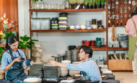 In a family business, a mother, son, and daughter manage a ceramic shop together, arranging tableware displays and coordinating daily operations for both retail and wholesale sales.の写真素材