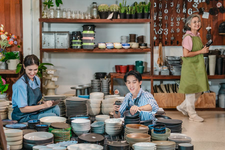 In a family business, a mother, son, and daughter manage a ceramic shop together, arranging tableware displays and coordinating daily operations for both retail and wholesale sales.の写真素材