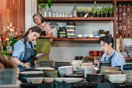 In a family business, a mother, son, and daughter manage a ceramic shop together, arranging tableware displays and coordinating daily operations for both retail and wholesale sales.の写真素材