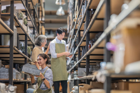 Mother and owner educates her children in family business warehouse. Material selection, product quality, sustainable recycling practices to improve production efficiency and eco friendly operationsの写真素材
