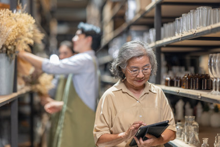 Mother and owner educates her children in family business warehouse. Material selection, product quality, sustainable recycling practices to improve production efficiency and eco friendly operationsの写真素材