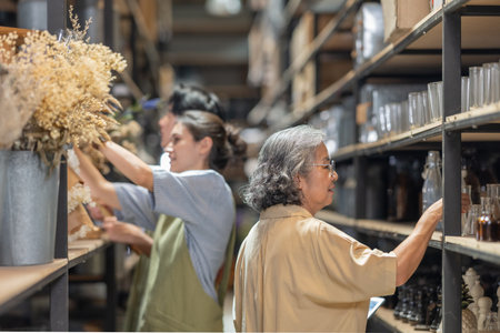 Mother and owner educates her children in family business warehouse. Material selection, product quality, sustainable recycling practices to improve production efficiency and eco friendly operationsの写真素材
