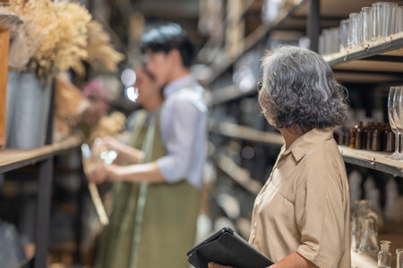 Mother and owner educates her children in family business warehouse. Material selection, product quality, sustainable recycling practices to improve production efficiency and eco friendly operationsの写真素材