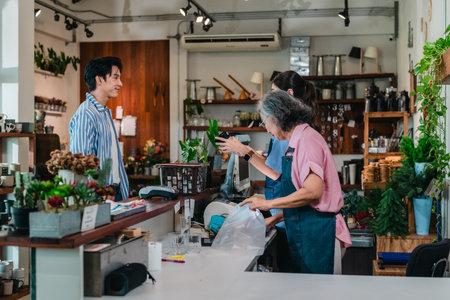 At a family run ceramic store, a mother and daughter provide friendly service to a male customer at the counter, highlighting warm retail hospitality and homeware shopping.の写真素材