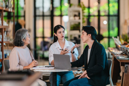 An Asian male investor and team meet with senior female owner at family business ceramic retail shop, negotiating and signing a partnership contract to expand retail and wholesale opportunities.の写真素材