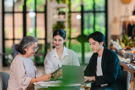 An Asian male investor and team meet with senior female owner at family business ceramic retail...