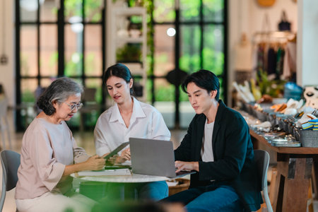 An Asian male investor and team meet with senior female owner at family business ceramic retail shop, negotiating and signing a partnership contract to expand retail and wholesale opportunities.の写真素材