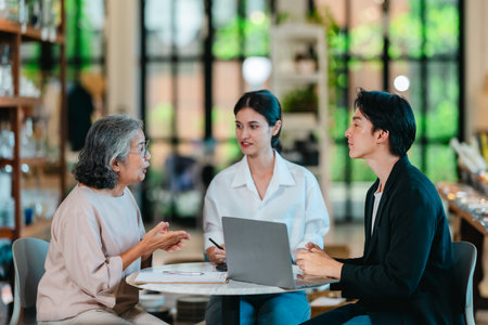 An Asian male investor and team meet with senior female owner at family business ceramic retail...