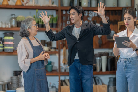 An Asian male investor and team meet with senior female owner at family business ceramic retail...