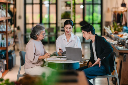 An Asian male investor and team meet with senior female owner at family business ceramic retail shop, negotiating and signing a partnership contract to expand retail and wholesale opportunities.の写真素材