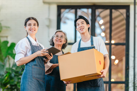 Mother, daughter, and son pose outside their family run ceramic shop and warehouse, presenting a friendly, professional team ready for retail and wholesale customers.の写真素材