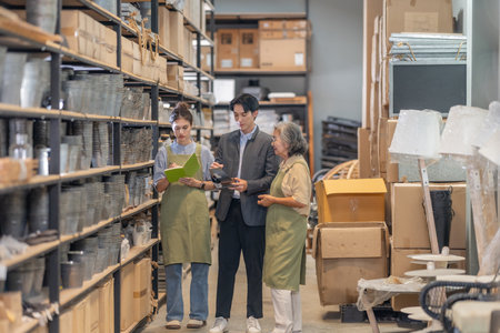 A male Asian investor visits a family run ceramic warehouse, guided by two female owners during a product tour and business discussion about purchasing and wholesale partnership opportunities.の写真素材