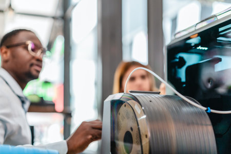 Two product designers examine and discuss 3D printed prototypes in design studio. Highlighting teamwork, creativity, and hands-on testing in product development using additive manufacturing technologyの写真素材