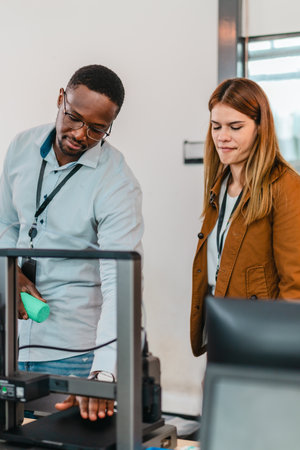 Two product designers examine and discuss 3D printed prototypes in design studio. Highlighting teamwork, creativity, and hands-on testing in product development using additive manufacturing technologyの写真素材