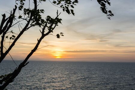 A scenery of sea at sunset with a shadow of tree at the side of photo in Chanthaburi, Thailand.の写真素材